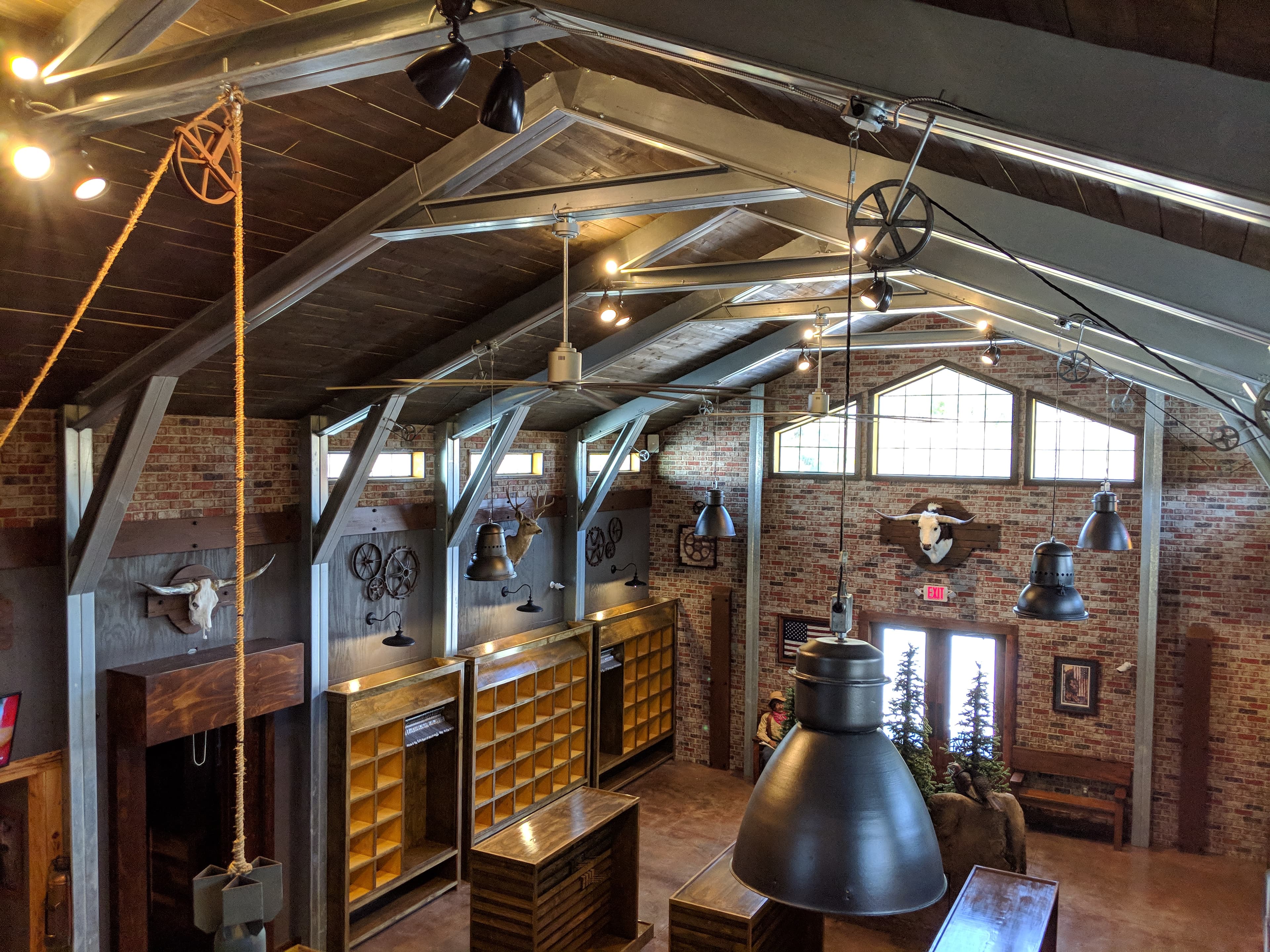 Rustic interior with vaulted ceilings, brick walls, industrial lighting, wooden shelves, and animal skulls.