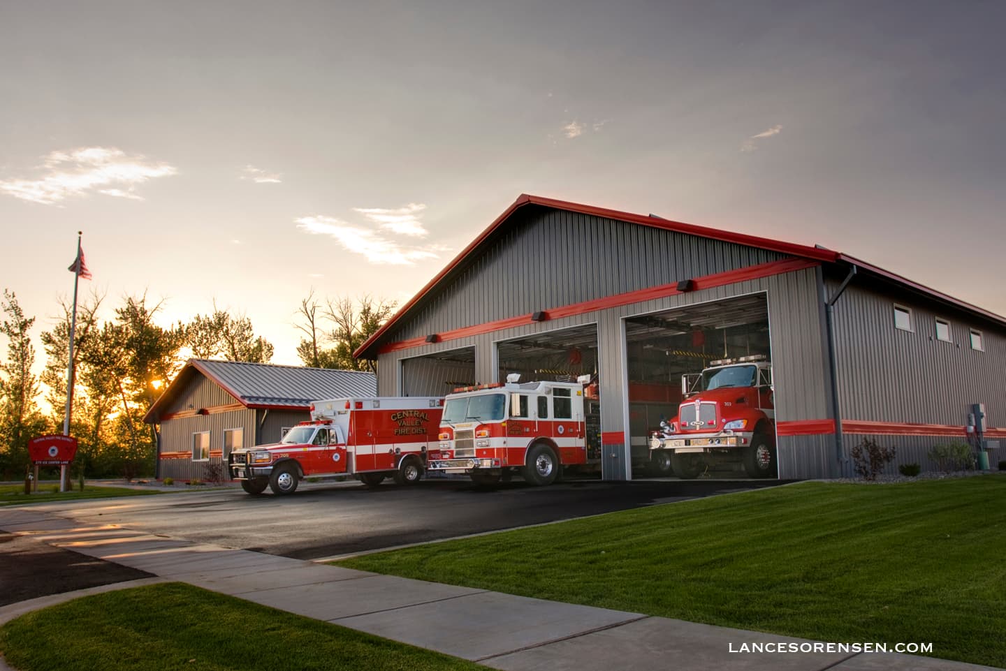 Central Valley fire trucks parked outside a modern grey station during a golden sunset.